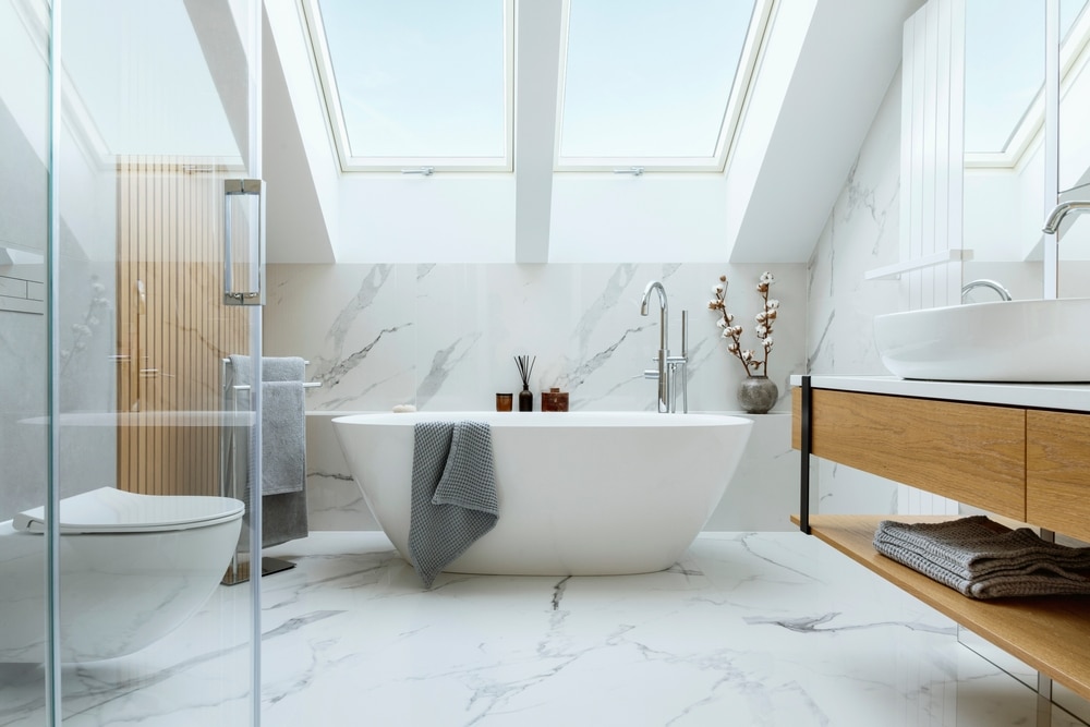 Modern bathroom featuring a freestanding tub, shower, wooden accents, and marble tiling in a bright, airy space