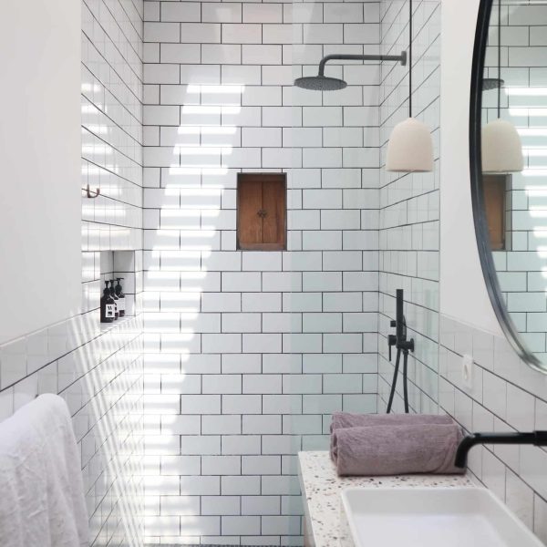 Bright ensuite bathroom with white subway tiles, a round mirror, modern fixtures, and a skylight illuminating the space
