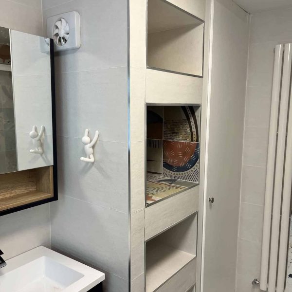Modern family bathroom featuring a sleek vanity, mirror, open shelving, and a towel radiator against light tiles