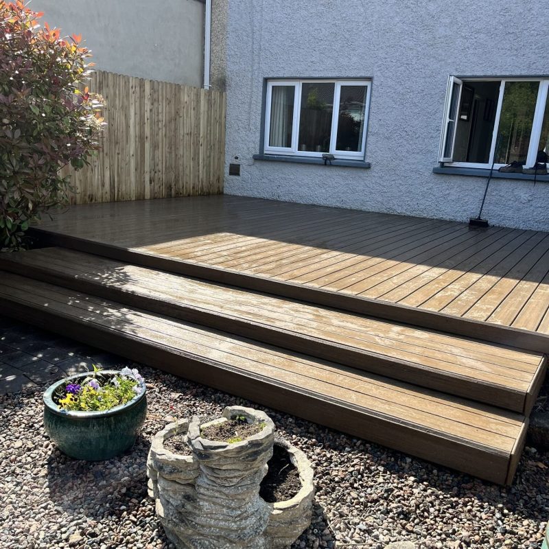 Wooden deck with steps, surrounded by gravel and potted plants, against a house wall in a sunny backyard. SEAI Grants Limeric
