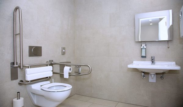 Mobility Bathroom1 Accessible mobility bathroom with grab bars, a toilet, sink, and a mirror, designed for safety and ease of use in renovations
