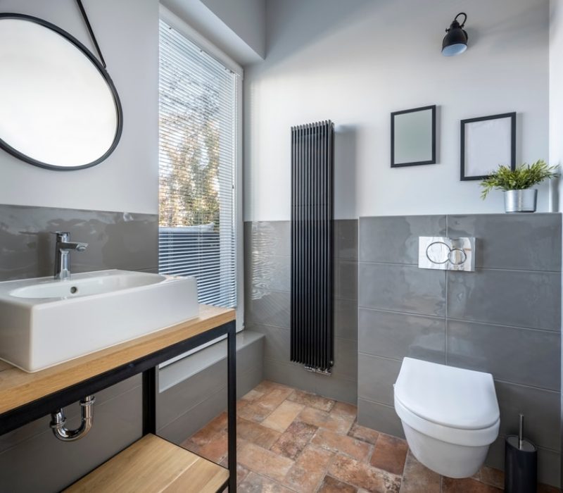 Modern bathroom featuring a vessel sink, a wall-mounted toilet, and stylish decor elements, highlighting bathroom fitters’ de